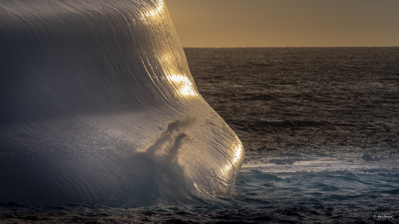 The wall of an iceberg lit at sunset